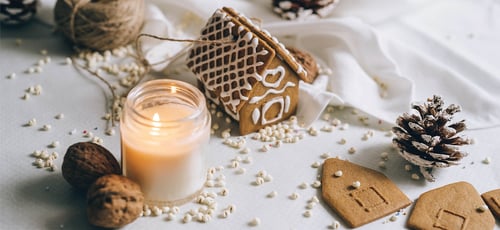 Table surface with candle, gingerbread house, and other holiday decorations Table surface with candle, gingerbread house, and other holiday decorations